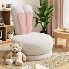 a white chair with pink bunny ears on it and a teddy bear sitting in front of it