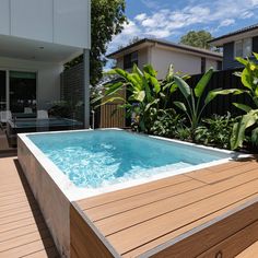 an outdoor hot tub in the middle of a decked area with trees and plants