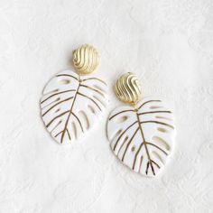 Without a doubt, we love monstera. When you and your outfit demand a bit more statement, these delightful gold and white porcelain monstera leaf earrings can be your answer. Every leaf vein is hand-painted with gold luster. Please handle our porcelain leaves with care as they can be quite fragile. MATERIAL: Handmade porcelain with gold luster; Gold plated; Gold filled. Gold- or silver-plated colour will fade over time. This is a normal result from long-term wear and contact with air. However, wi Handmade White Leaf-shaped Jewelry, Handmade White Leaf-shaped Earrings, White Leaf-shaped Jewelry Gift, Luxury Handmade White Earrings, Luxury White Handmade Earrings, Monstera Leaf Earrings, Sparkly Necklace, Alphabet Jewelry, Handmade Porcelain