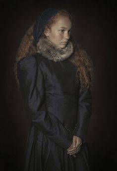 a woman with long hair wearing a black dress and a fur stole around her neck