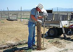 a man standing next to a wooden bench in the middle of an open field,