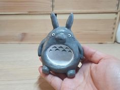 a hand holding a small toy with a face on it's body and ears