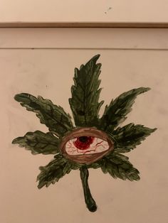 a drawing of a leaf with an eye in it's center, on a white wall