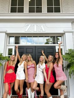 four beautiful young women standing next to each other in front of a door with their arms up