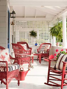 a porch with red wicker furniture and potted plants