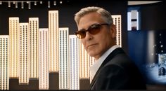 a man wearing sunglasses and a suit in front of a wall with lights on it