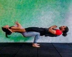 a man and woman doing yoga poses in front of a wall