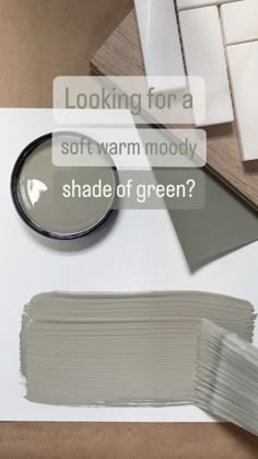 some white paint sitting on top of a table with the words looking for soft warm mouldy shade of green?