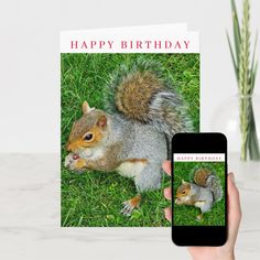 a person holding up a card with a squirrel on it and a cell phone next to it