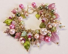 Make a statement with this one-of-a-kind floral charm bracelet. Gold wire wrapped freshwater pearls, glass pearls, cut Swarovski crystals, Czech glass flowers and leaves, gold plated findings, and assorted glass beads are hung on a gold-plated chain and finished with a matching toggle clasp.  This bright and colorful beaded bracelet comes with all charms shown. Bracelet length can be adjusted as requested, prior to checkout, by selecting a size. Makes a great addition to your collection or a won Elegant Beaded Dangle Charm Bracelet, Whimsical Handmade Pearl Jewelry, Whimsical Pink Bracelet Jewelry, Elegant Pink Wire Wrapped Bracelets, Pink Charms Jewelry For Wedding, Elegant Pink Dangle Charm Bracelet, Pink Wire Wrapped Bracelet Jewelry, Pink Wire Wrapped Bracelet, Whimsical Beaded Jewelry For Wedding