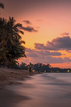 the sun is setting at the beach with palm trees