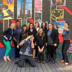 a group of people posing for a photo in front of a wall covered with posters