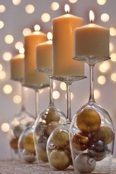 candles are lined up in wine glasses with balls and baubles around them on a table