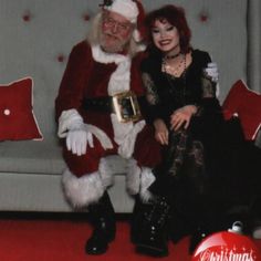 a man and woman dressed as santa claus sitting on a couch