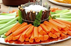 carrots and celery arranged on a platter with dip in the middle