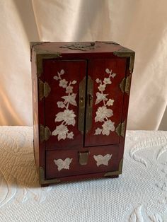 a small wooden cabinet with white flowers on it