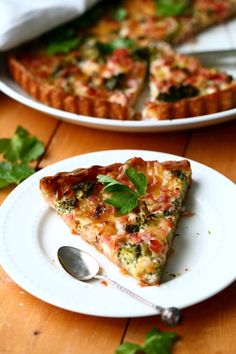 a slice of quiche on a white plate with a fork and knife next to it