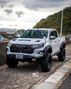 a white toyota pickup truck parked on the side of the road with mountains in the background