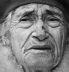 an old woman with wrinkles and a hat on her head is looking at the camera