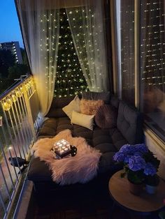 a couch sitting on top of a wooden floor next to a window covered in lights