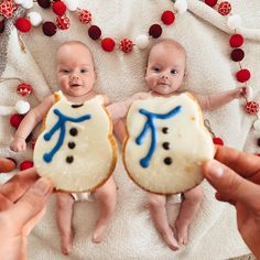 two babies are being held by their moms hands while they have cookies in front of them