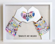 a white frame with colorful bracelets and a heart shaped paper cutout in the middle