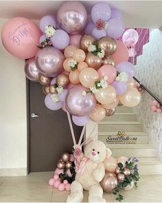 a teddy bear sitting under a bunch of balloons