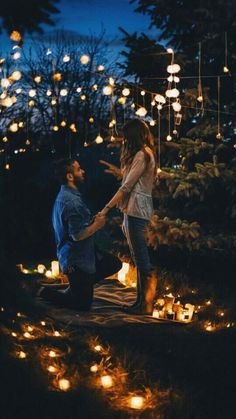 two people holding hands in the dark surrounded by lit up lanterns and trees at night