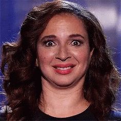 a close up of a person wearing a black shirt and smiling at the camera with an intense look on her face