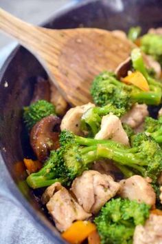 broccoli and chicken stir fry in a wok with a wooden spatula