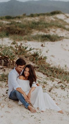 a man and woman are sitting on the sand