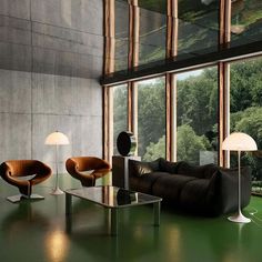 a living room filled with furniture next to large windows on top of a green floor