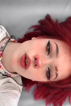 a young woman with red hair and piercings on her face is posing for the camera