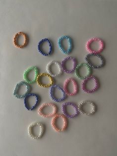 several different colored bracelets on a white surface with one bead in the middle