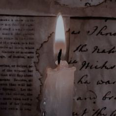 a lit candle sitting on top of a piece of paper next to an old letter