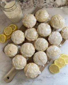 lemon muffins with icing on a cutting board next to sliced lemons