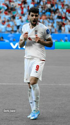 a soccer player running on the field with his mouth open and people in the stands watching