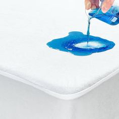 someone is painting the bottom of a mattress with blue watercolors and white sheets