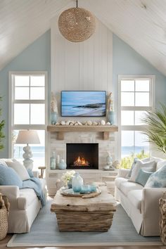 Coastal living room featuring an electric fireplace with a TV above and stylish wall storage, creating a harmonious decor. Electric Fireplace Ideas With Tv Coastal, Fireplace On Window Wall, Beach House Tv Wall, Coastal Stone Fireplace, Coastal Living Room Tv, Coastal Fireplace Ideas Beach Styles, Fireplace Beach House, Coastal Tv Room, Coastal Tv Wall