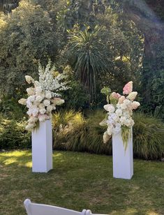 two tall white vases filled with flowers on top of grass