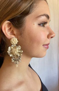 Colleen Toland  Grand Fleur Earring in the color Latte.  The small flowers in the center are cream colored and hand beaded together in a cluster with gold seed beads. The petals are hand colored in a smokey quartz color fading into cream. The drop beads are a lovely cream colored glass pearl bead.  So pretty and unique and the neutral cream color easy to match with wardrobe choices. These work for bridal or for just everyday chic. Length is approx 3.5 inches, width is approx 1.75 inches. The stud is a hypo allergenic and the closure is a push back.  These earrings can be converted to clip upon request. This is a quality piece of jewelry that will last a life time. Created by designer Colleen Toland who has been creating her unique style of vintage jewelry for more than 30 years. All of our Elegant Beige Flower Earrings Gift, Elegant Beige Flower Earrings For Gift, Elegant Cream Flower Earrings For Weddings, Cream Pearl Earrings For Party, Gold Beaded Flower Earrings For Party, Handmade Cream Flower Earrings, Flower Statement Earrings, Quartz Color, Quartz Colors