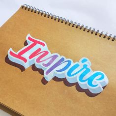 a spiral notebook with the word inspire written in large letters on it, next to a pen