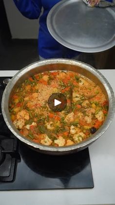 a pan on top of a stove with food in it and someone holding a spatula