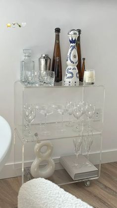 a clear shelf with wine glasses and bottles on it