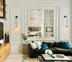 a living room filled with furniture and a large mirror on the wall above it's windows