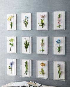 a book sitting on top of a table in front of a wall mounted with flowers