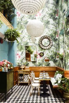 the interior of a restaurant decorated with tropical wallpaper and potted plants on the walls