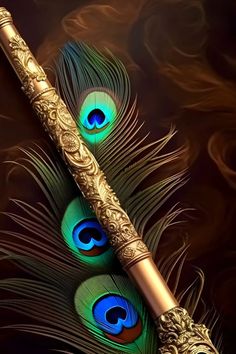 two peacock feathers are next to a golden fountain pen with blue and green lights on it