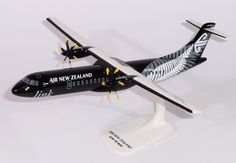 an air new zealand model airplane on a white surface with black and yellow trimmings