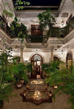 an indoor courtyard with potted plants and lights on the ceiling is lit up at night